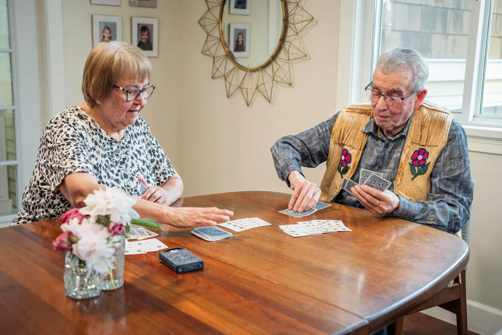 An older woman and man playing cards at a wooden table