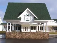 A white Drews Place home in Hillsdale with a green roof and stone front