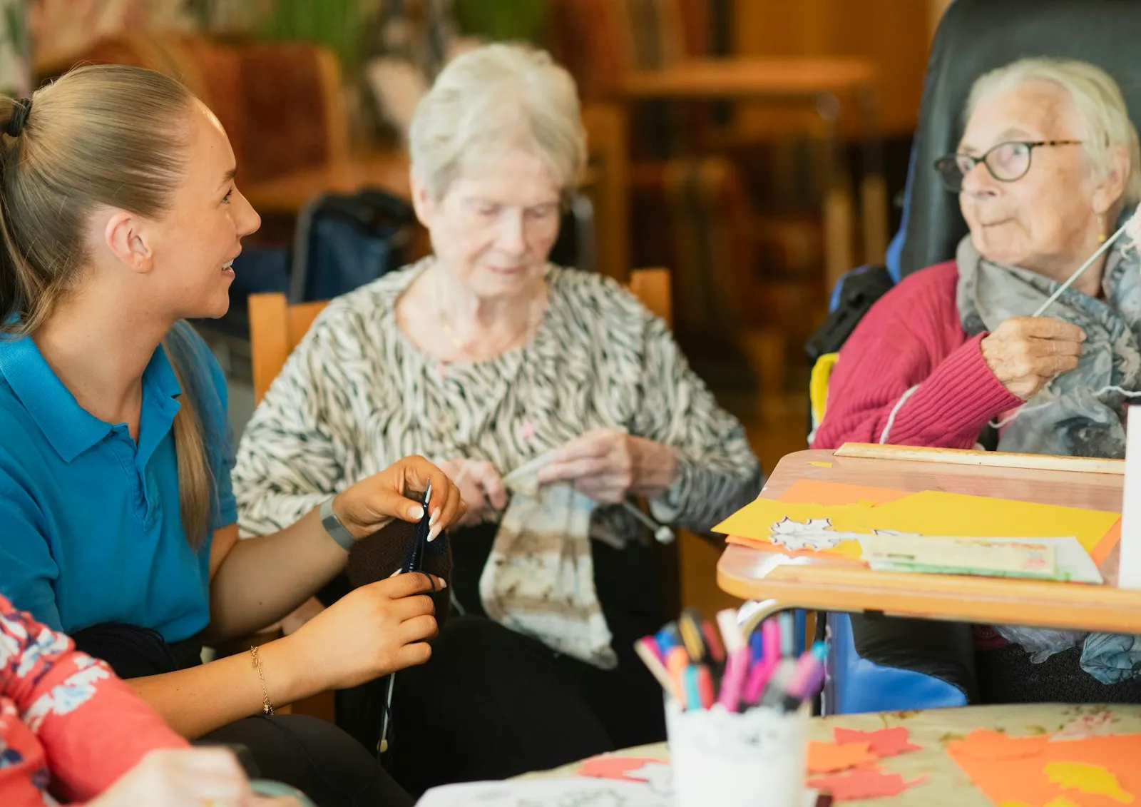 A caregiver knitting alongside two older women