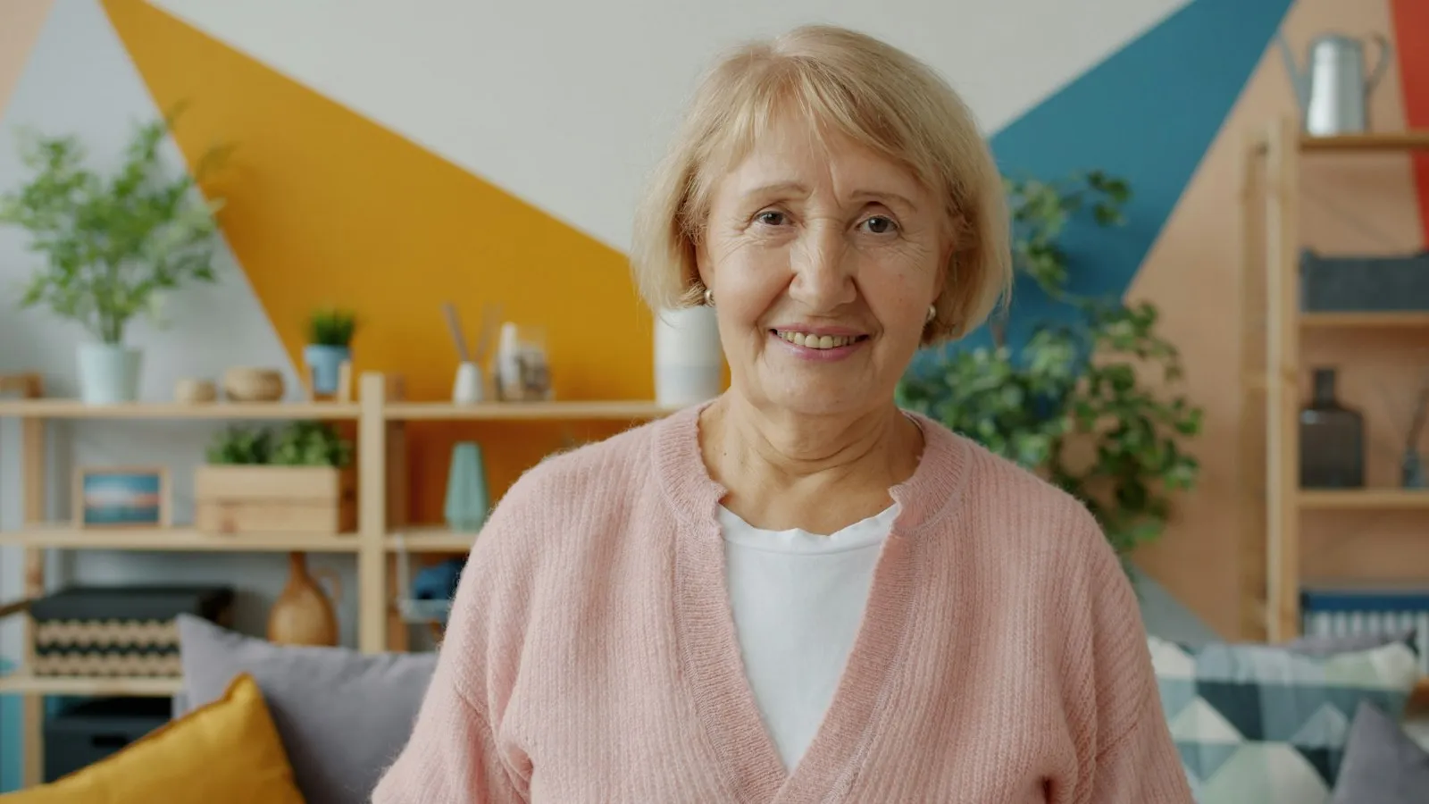 A smiling older woman in a pink cardigan